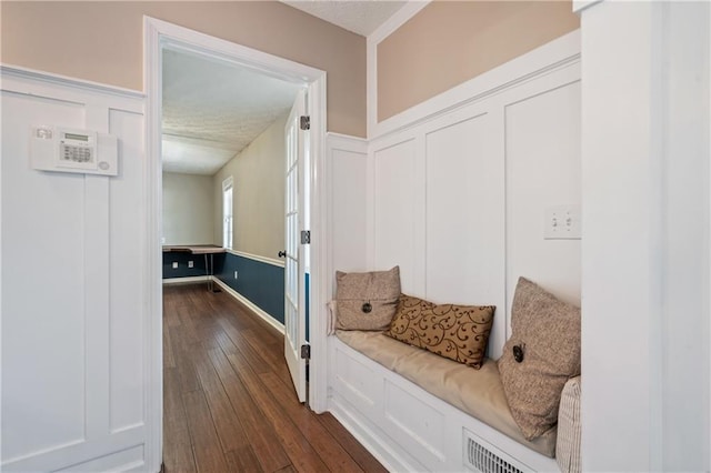 mudroom with a wainscoted wall, a decorative wall, and dark wood-style flooring