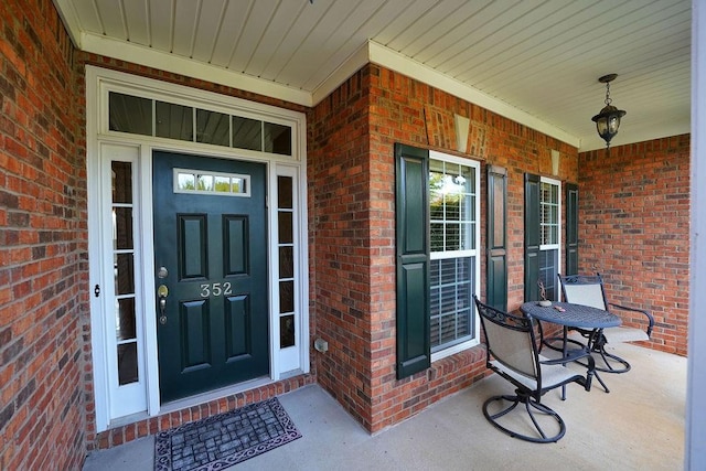 property entrance featuring a porch and brick siding