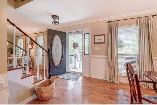 foyer with light hardwood / wood-style flooring, crown molding, and a wealth of natural light