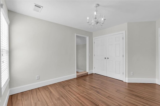 335 Pintail Ct, Suwanee, GA 30024 - unfurnished bedroom with a chandelier, baseboards, a closet, wood finished floors, and multiple windows