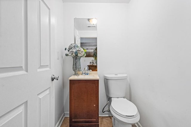 half bath with toilet, baseboards, and vanity
