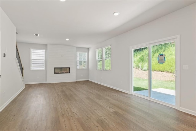 7127 Brushwood Bnd, Lithonia, GA 30058 - unfurnished living room with light wood-type flooring, recessed lighting, a large fireplace, and baseboards