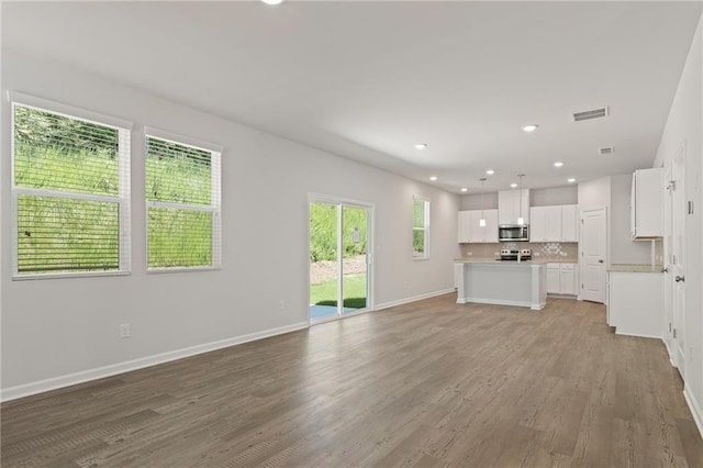 7127 Brushwood Bnd, Lithonia, GA 30058 - unfurnished living room featuring recessed lighting, light wood finished floors, visible vents, and baseboards