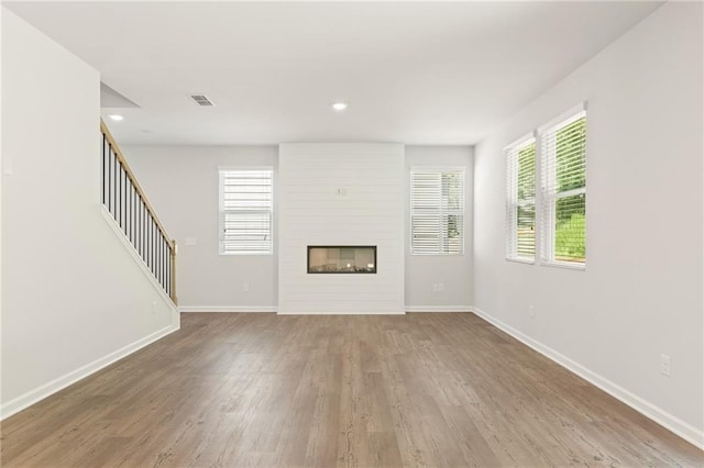 7127 Brushwood Bnd, Lithonia, GA 30058 - unfurnished living room with a large fireplace, visible vents, wood finished floors, and baseboards