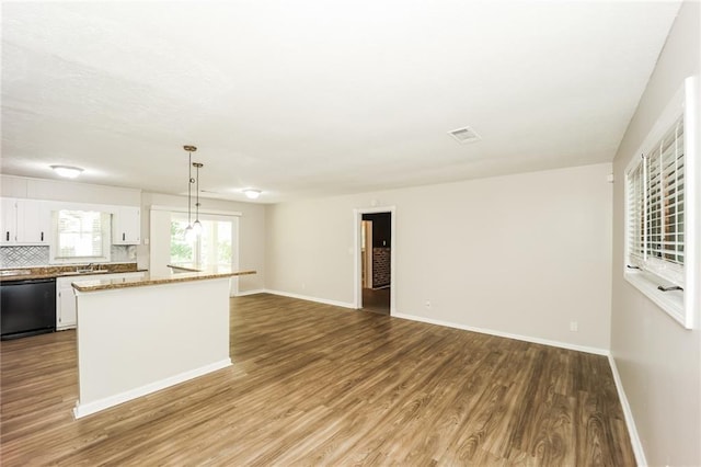 kitchen featuring white cabinetry, wood-type flooring, hanging light fixtures, dishwasher, and backsplash