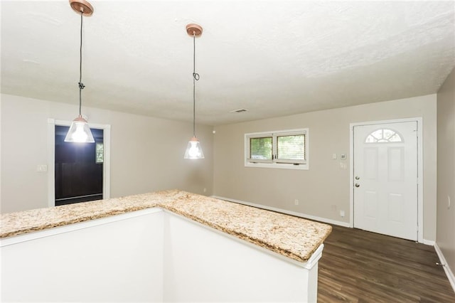 kitchen featuring pendant lighting, white cabinetry, light stone countertops, and dark wood-type flooring