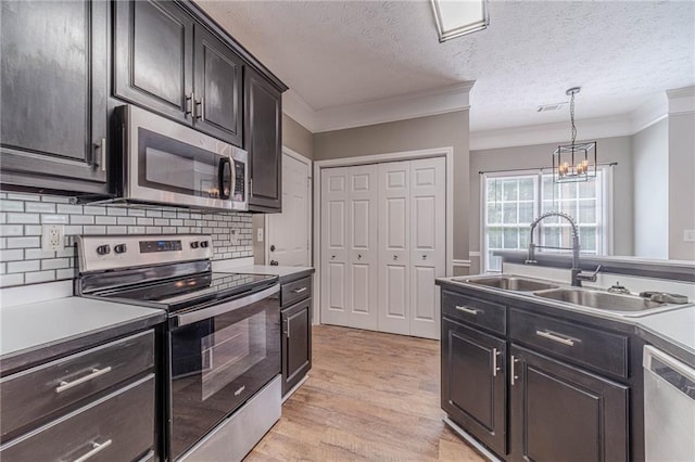 206 Belmont Dr, Monroe, GA 30655 - kitchen with appliances with stainless steel finishes, a sink, crown molding, light wood-style flooring, and backsplash