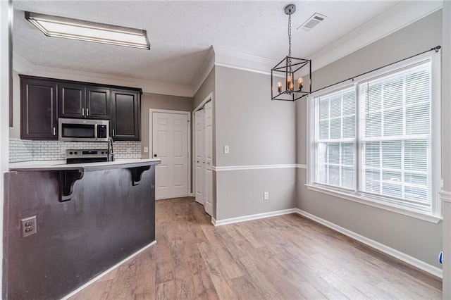 206 Belmont Dr, Monroe, GA 30655 - kitchen with appliances with stainless steel finishes, a breakfast bar, light countertops, a chandelier, and decorative backsplash