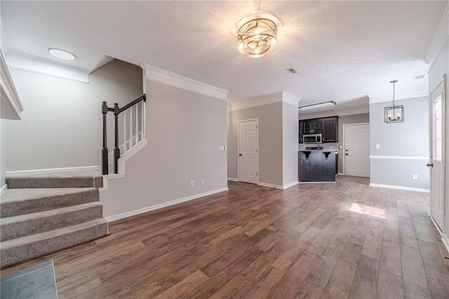 206 Belmont Dr, Monroe, GA 30655 - unfurnished living room featuring ornamental molding, stairs, dark wood-style flooring, a textured ceiling, and a chandelier