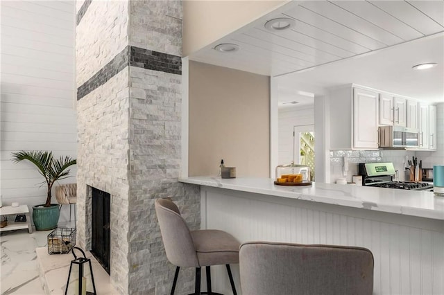 5219 Legendary Ln, Acworth, GA 30102 - kitchen with appliances with stainless steel finishes, light stone countertops, marble look tiles, and a breakfast bar area
