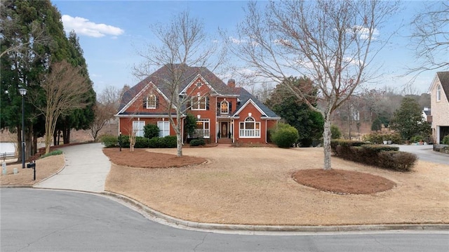 view of front facade featuring curved driveway and a chimney