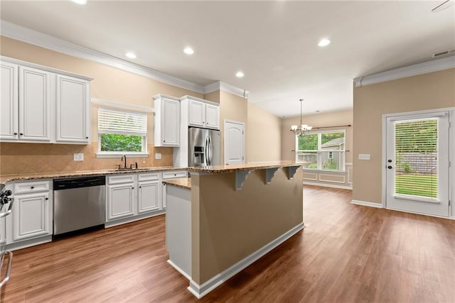 kitchen featuring white cabinetry, stainless steel appliances, wood-type flooring, and a center island