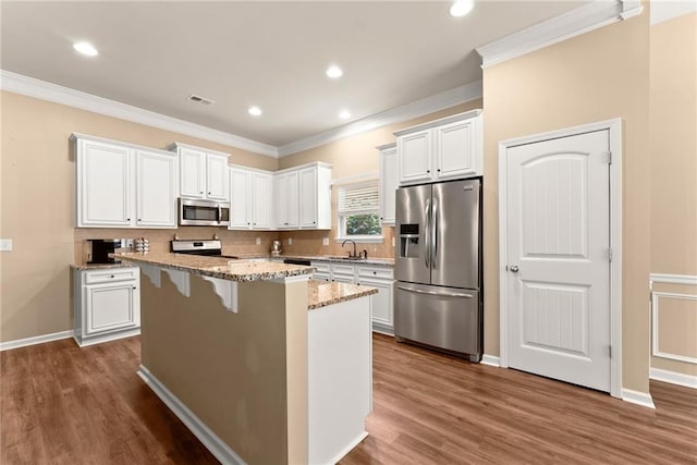 kitchen with dark hardwood / wood-style flooring, a center island, white cabinets, light stone countertops, and appliances with stainless steel finishes