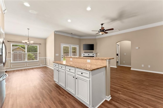 kitchen featuring white cabinets, decorative light fixtures, crown molding, and a center island