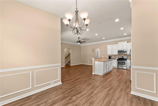 kitchen featuring white cabinets, hardwood / wood-style flooring, ornamental molding, appliances with stainless steel finishes, and decorative light fixtures