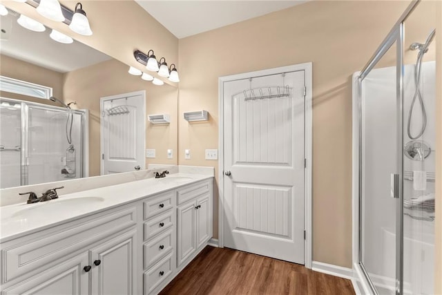 bathroom with hardwood / wood-style floors, vanity, and a shower with door