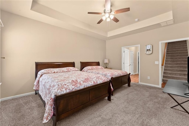 carpeted bedroom featuring ceiling fan and a tray ceiling