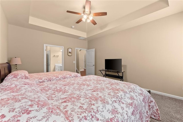 bedroom featuring a tray ceiling, carpet, ceiling fan, and ensuite bath