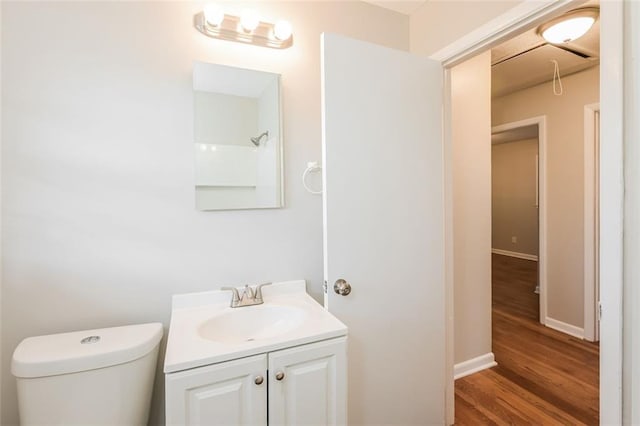 bathroom featuring vanity, toilet, wood finished floors, and baseboards