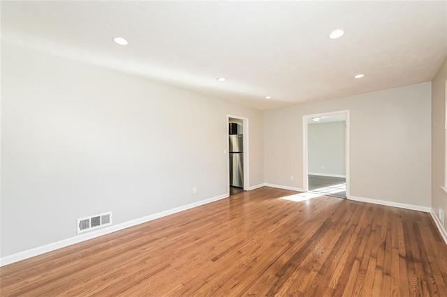 empty room featuring visible vents, recessed lighting, baseboards, and wood finished floors