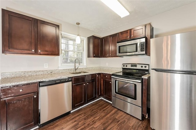 kitchen featuring light stone counters, dark wood-style floors, a sink, dark brown cabinets, and appliances with stainless steel finishes