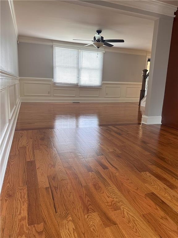 1055 Worthington Hills Dr, Roswell, GA 30076 - spare room with a wainscoted wall, a decorative wall, ornamental molding, a ceiling fan, and wood finished floors
