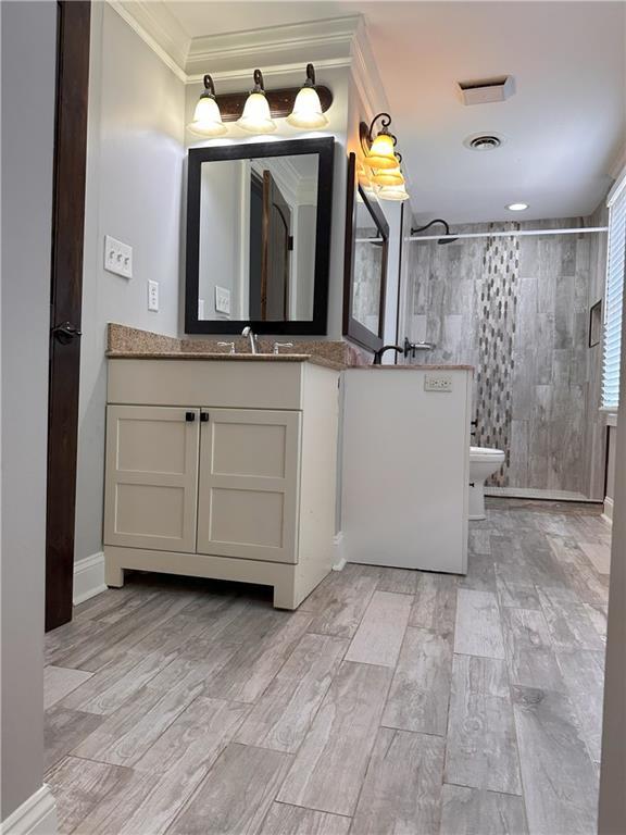 1055 Worthington Hills Dr, Roswell, GA 30076 - bathroom with wood finished floors, crown molding, tiled shower, vanity, and baseboards