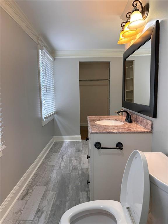 1055 Worthington Hills Dr, Roswell, GA 30076 - bathroom with toilet, vanity, ornamental molding, wood finished floors, and baseboards