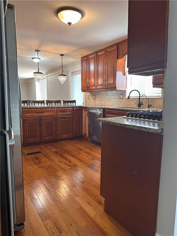1055 Worthington Hills Dr, Roswell, GA 30076 - kitchen featuring stainless steel appliances, crown molding, tasteful backsplash, dark wood-style floors, and hanging light fixtures