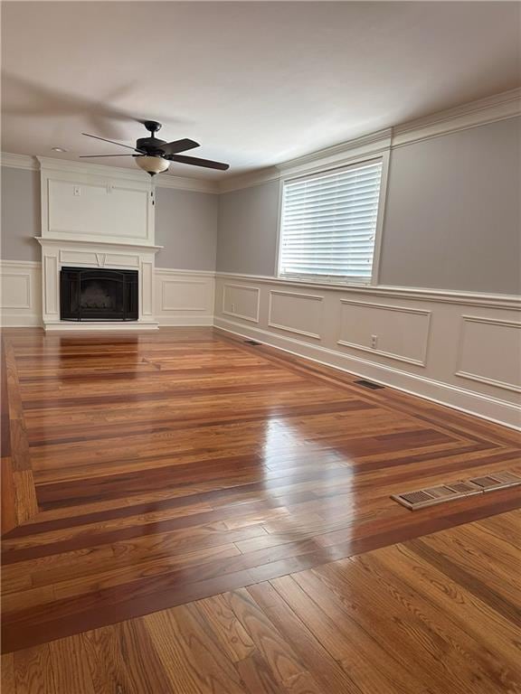 1055 Worthington Hills Dr, Roswell, GA 30076 - unfurnished living room featuring a decorative wall, a ceiling fan, ornamental molding, a wainscoted wall, and a fireplace with raised hearth
