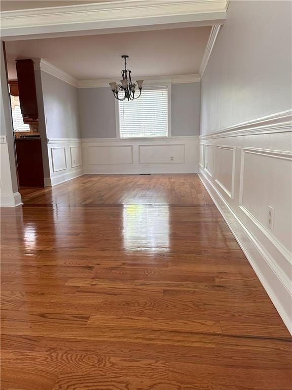 1055 Worthington Hills Dr, Roswell, GA 30076 - unfurnished dining area featuring a chandelier, crown molding, wood finished floors, wainscoting, and a decorative wall