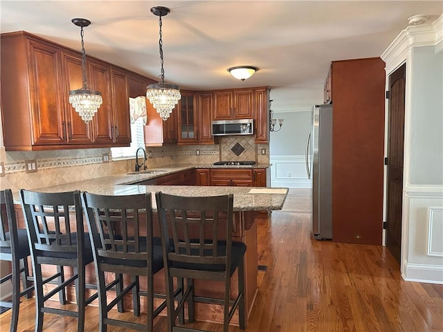 1055 Worthington Hills Dr, Roswell, GA 30076 - kitchen with appliances with stainless steel finishes, a sink, a chandelier, a peninsula, and brown cabinets