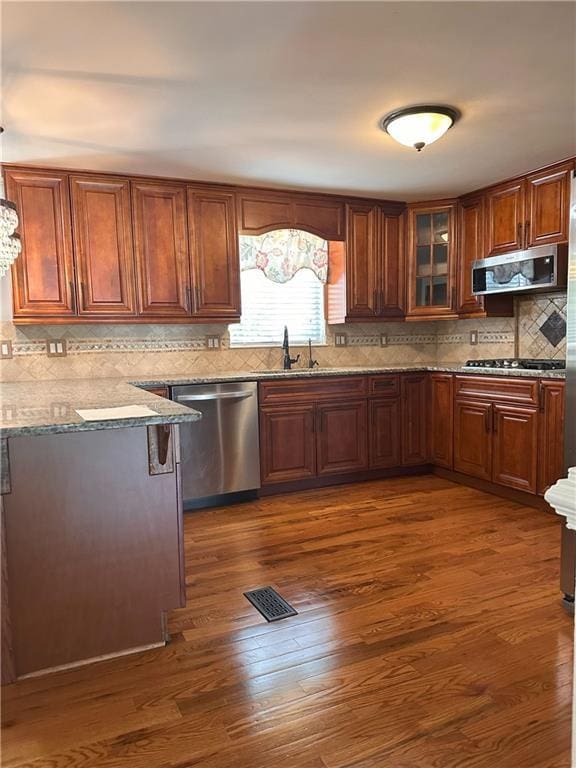 1055 Worthington Hills Dr, Roswell, GA 30076 - kitchen featuring stainless steel appliances, a sink, dark wood finished floors, tasteful backsplash, and glass insert cabinets