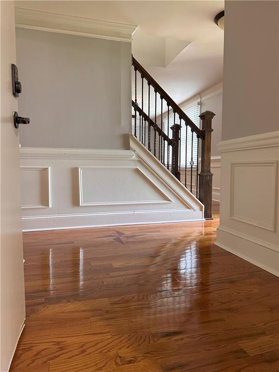 1055 Worthington Hills Dr, Roswell, GA 30076 - staircase featuring crown molding, a decorative wall, wood finished floors, and a wainscoted wall