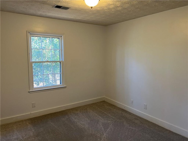 spare room with dark carpet and a textured ceiling