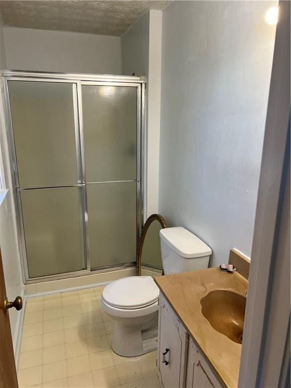 bathroom featuring walk in shower, vanity, toilet, and a textured ceiling