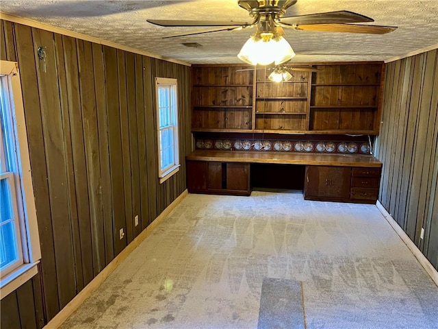 unfurnished office with built in desk, a textured ceiling, and wood walls