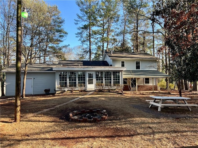 rear view of property with a sunroom and a fire pit