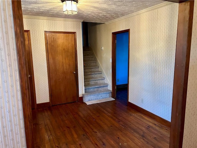 stairs with hardwood / wood-style floors, ornamental molding, and a textured ceiling