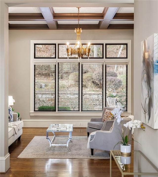 sitting room featuring a notable chandelier, coffered ceiling, wood finished floors, beam ceiling, and crown molding