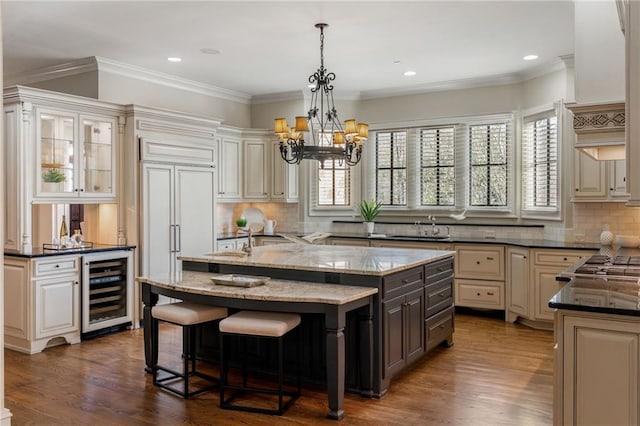 kitchen with dark stone counters, wine cooler, a sink, and a kitchen island