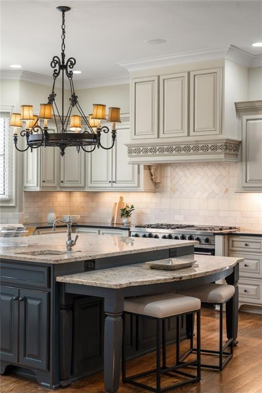 kitchen with ornamental molding, custom exhaust hood, light stone countertops, decorative light fixtures, and an inviting chandelier