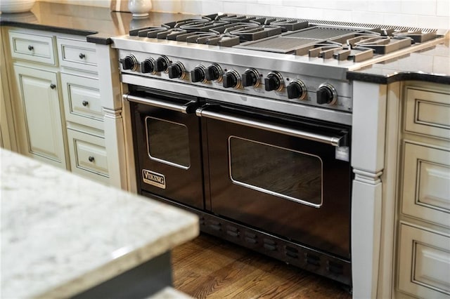 kitchen featuring range with two ovens, cream cabinets, and light stone countertops