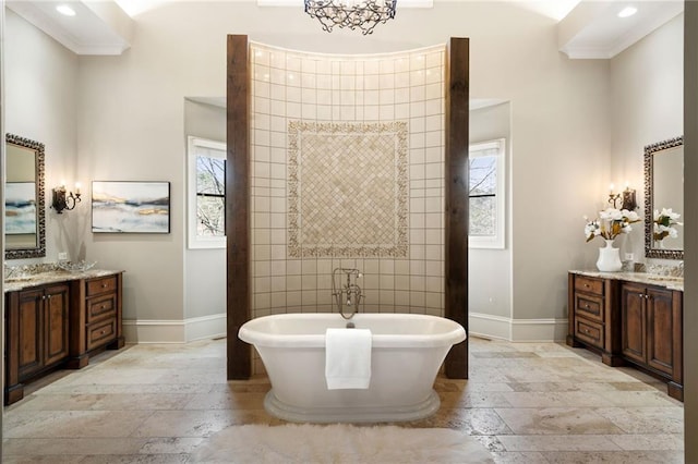 full bathroom with a soaking tub, vanity, stone tile flooring, and baseboards