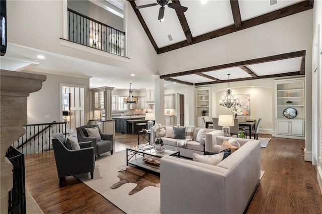 living room with ceiling fan with notable chandelier, beamed ceiling, dark wood finished floors, and built in features