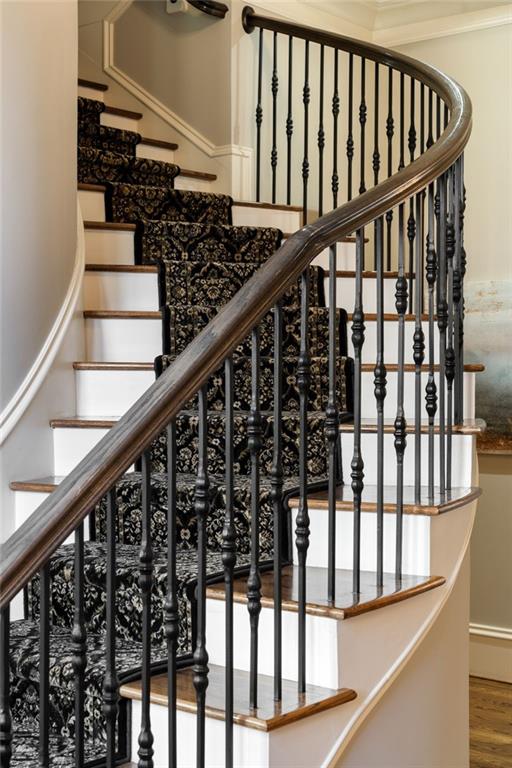 stairway with ornamental molding and wood finished floors