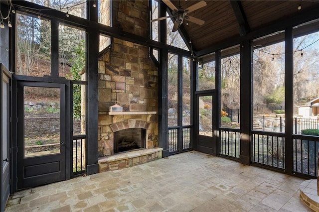 unfurnished sunroom with an outdoor stone fireplace, wooden ceiling, and plenty of natural light