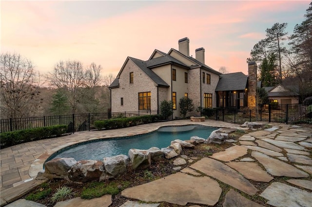 pool at dusk featuring a patio area, a fenced backyard, and a fenced in pool