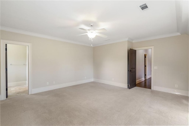 unfurnished room featuring light colored carpet, visible vents, ornamental molding, a ceiling fan, and baseboards