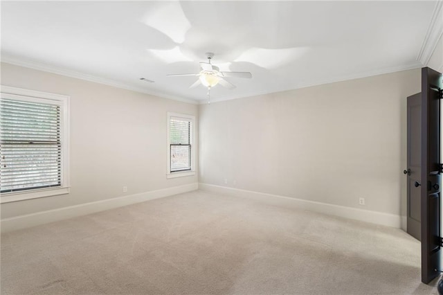 spare room featuring light carpet, visible vents, baseboards, ceiling fan, and crown molding